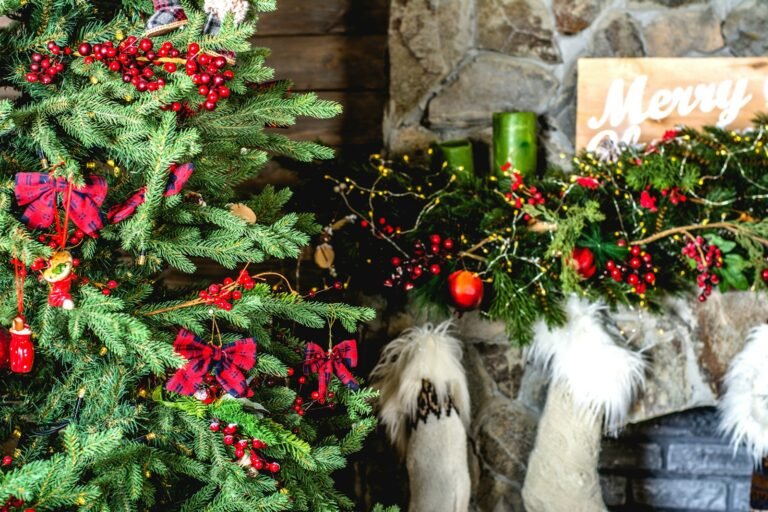 Pre-lit Christmas garland on a stone fireplace mantel with red berries, stockings and a decorated tree