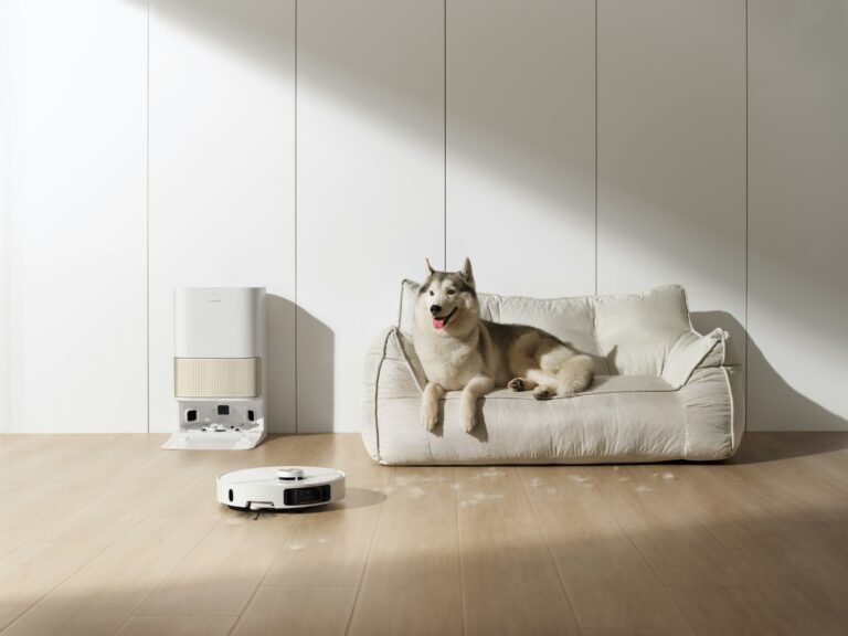 Best robot vacuum for pet hair: a white robot vacuum leaves its self-emptying dock while a husky rests on a light sofa