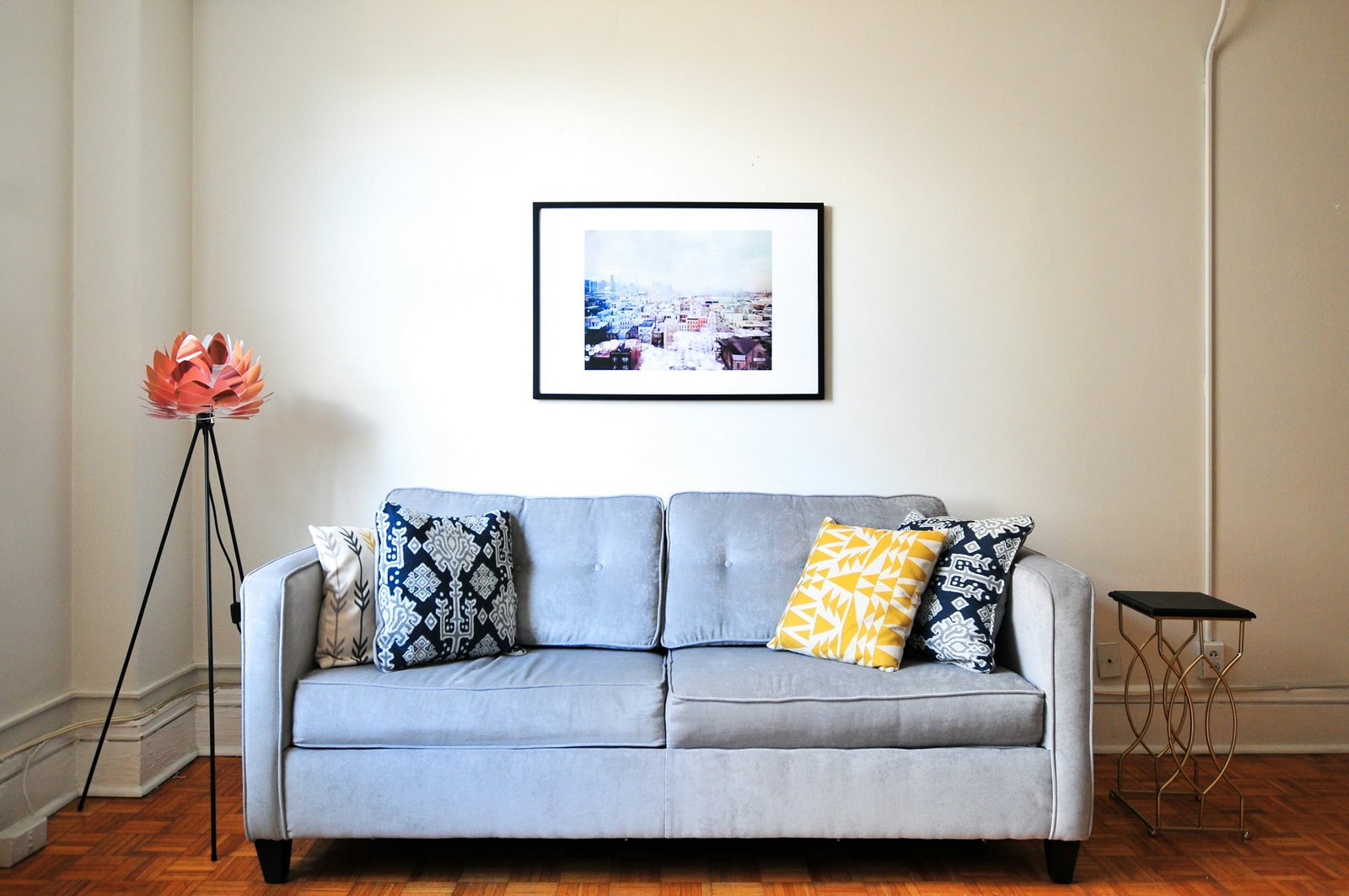 Best sleeper sofa for guests: a light gray tufted sofa with patterned pillows in a bright living room