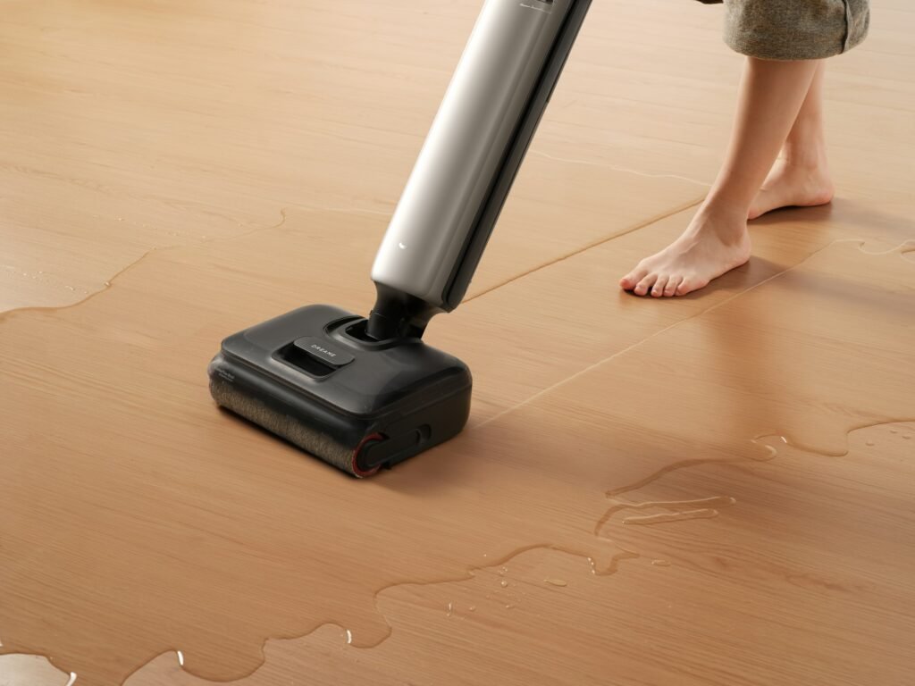 Steam mop vs spin mop vs wet-dry vacuum: a cordless wet-dry floor cleaner picking up a water spill on a wood-look floor