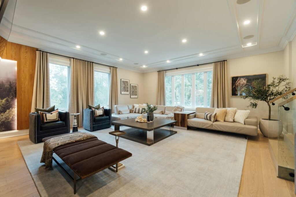 Upholstered storage ottoman bench with a throw blanket in a large living room with sofas, one of many storage ottomans for living room layouts