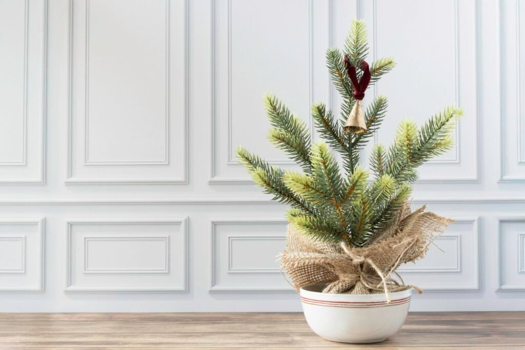 Tabletop Christmas tree: a small burlap-wrapped mini pine in a white bowl on a wooden table