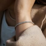 Best tennis bracelet on Amazon: a slim stone-set tennis bracelet worn on a woman's wrist with a cream wool coat