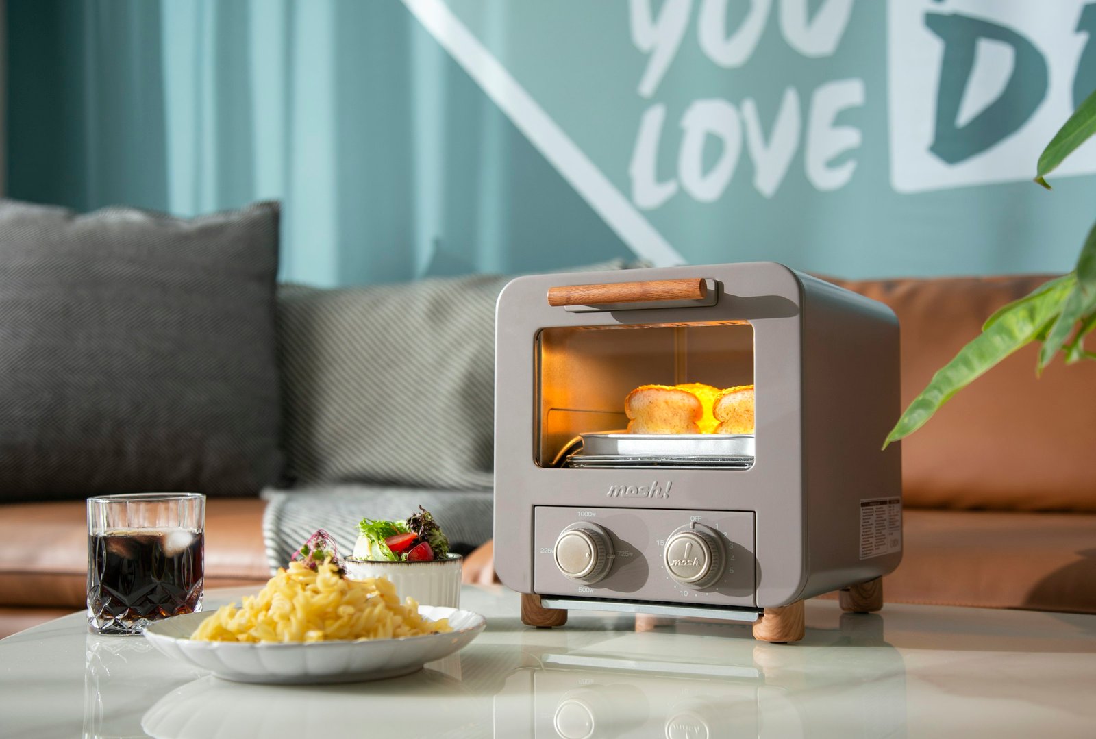 Best toaster oven on a bright coffee table toasting bread next to a plate of pasta