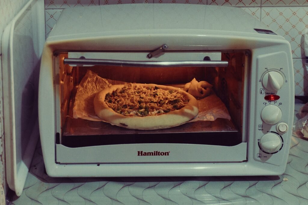 Large toaster oven baking a homemade pizza on parchment, showing countertop oven pizza capacity