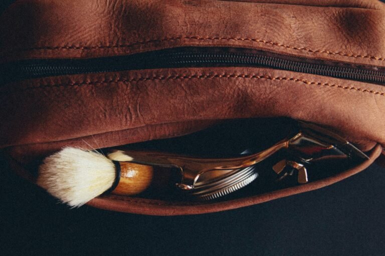 Best toiletry bag for men: a brown leather dopp kit holding a shaving brush and safety razor