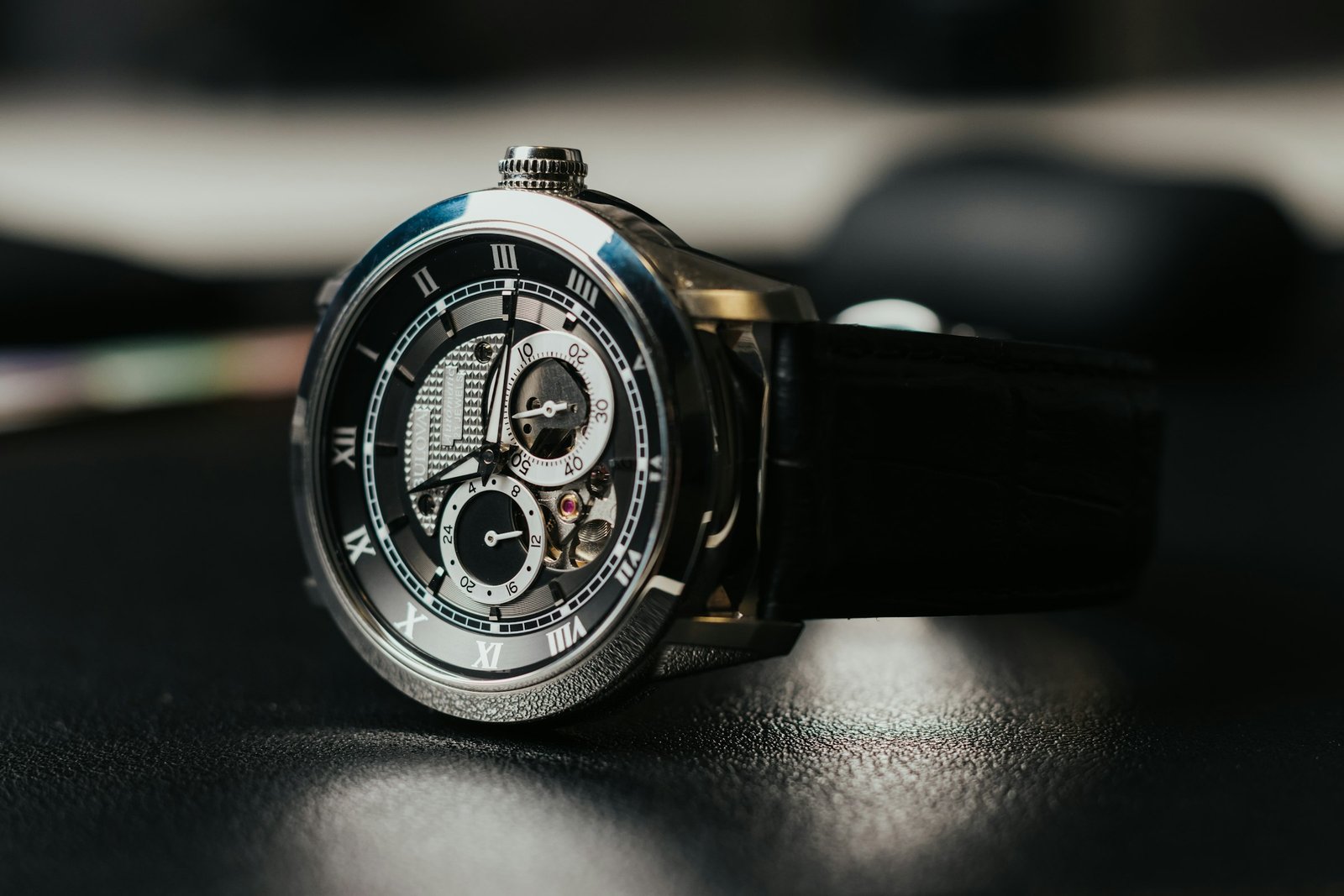 Best watch winder for automatic watches: an open-heart automatic watch with a black leather strap resting on a dark surface