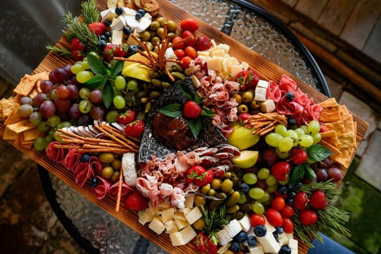Charcuterie board set idea: a large wooden board filled with cheeses, cured meats, grapes and crackers