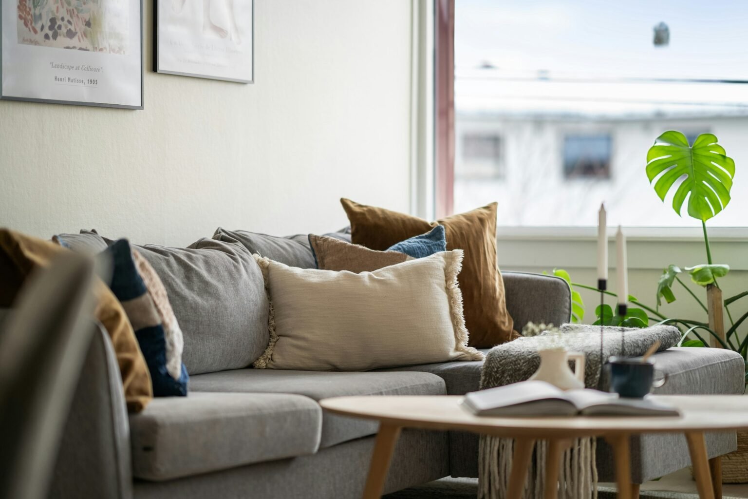 Chocolate brown throw pillows styled with cream and navy cushions on a light gray sectional beside a sunny window