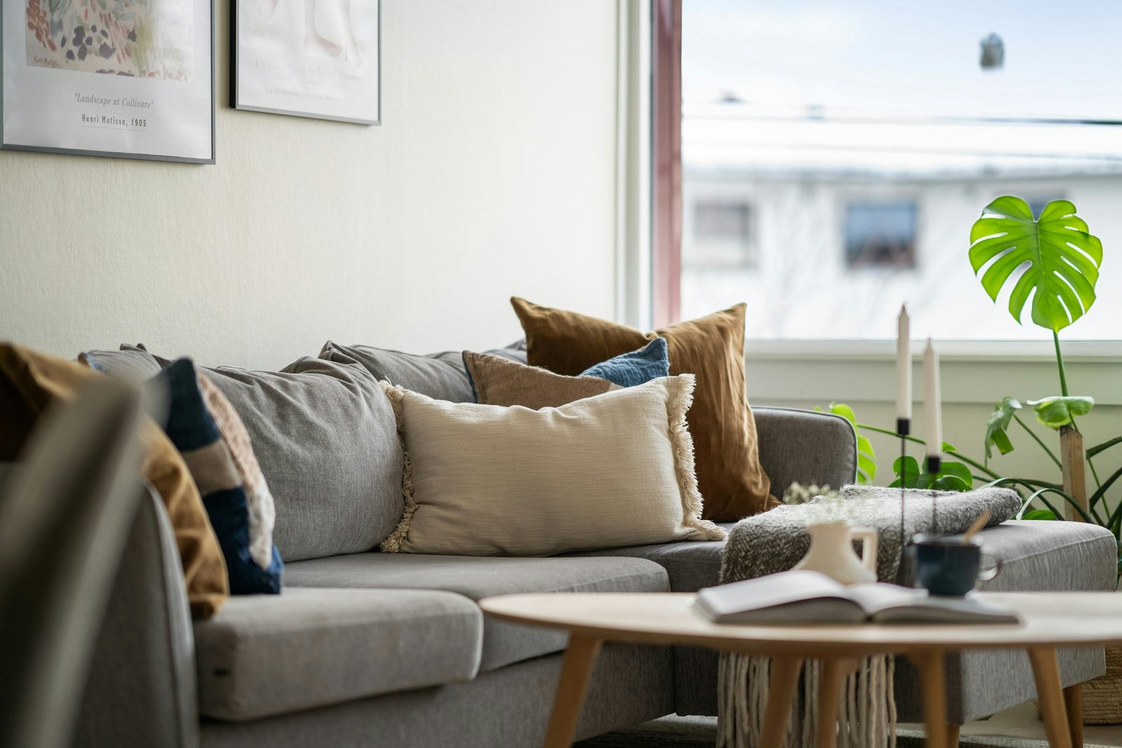 Chocolate brown throw pillows styled with cream and navy cushions on a light gray sectional beside a sunny window