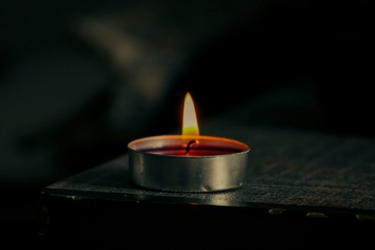 Plasma lighter review: a lit tealight candle on a dark wooden surface