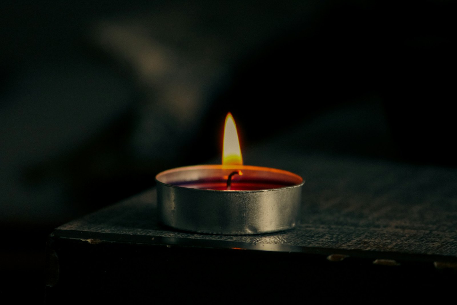 Plasma lighter review: a lit tealight candle on a dark wooden surface