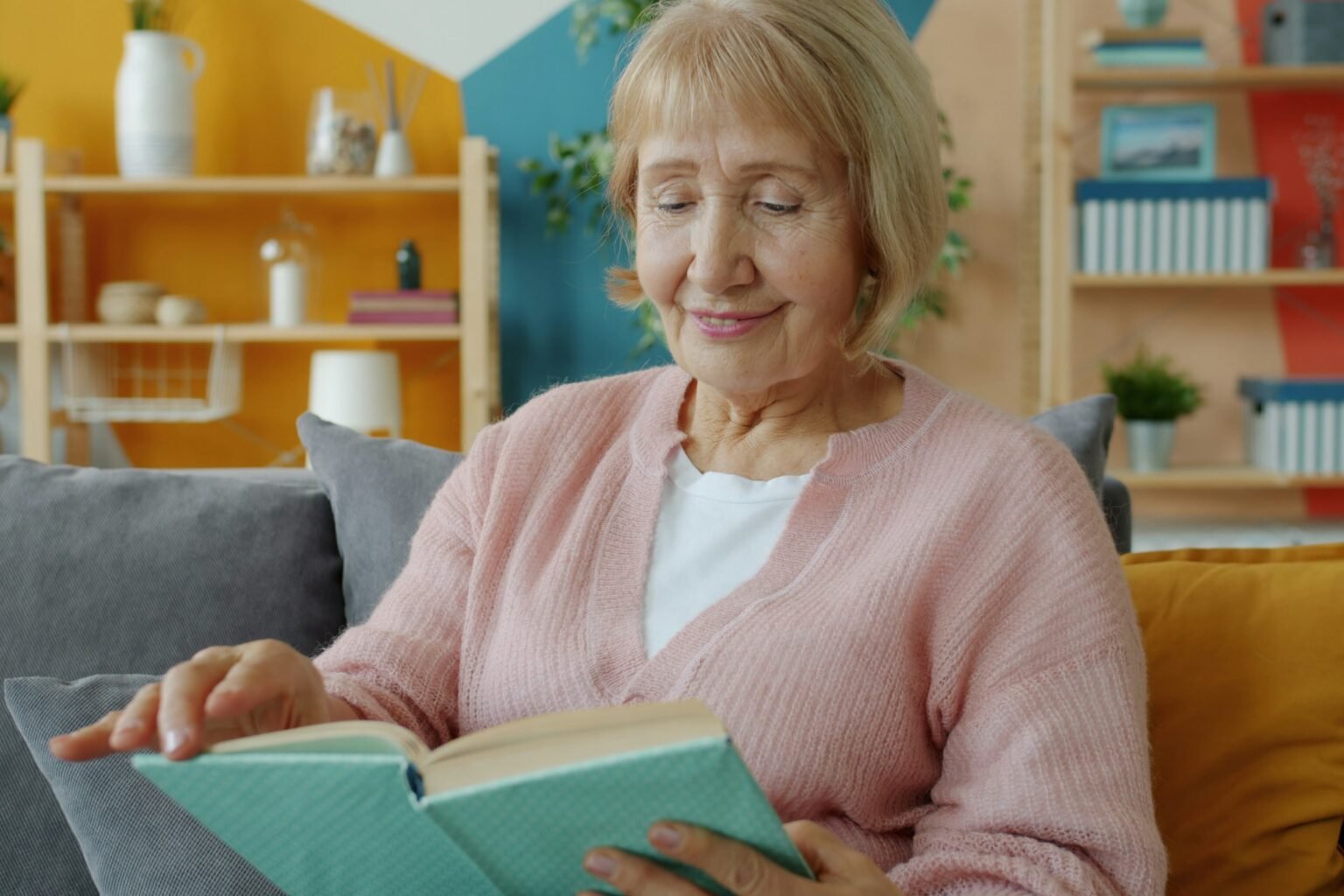 Digital calendar clock idea: a senior woman reading on a bright living room sofa