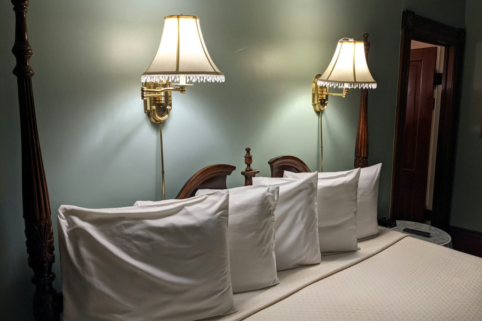 How to style euro pillows: a row of plump white pillows layered across a bed with wall sconces