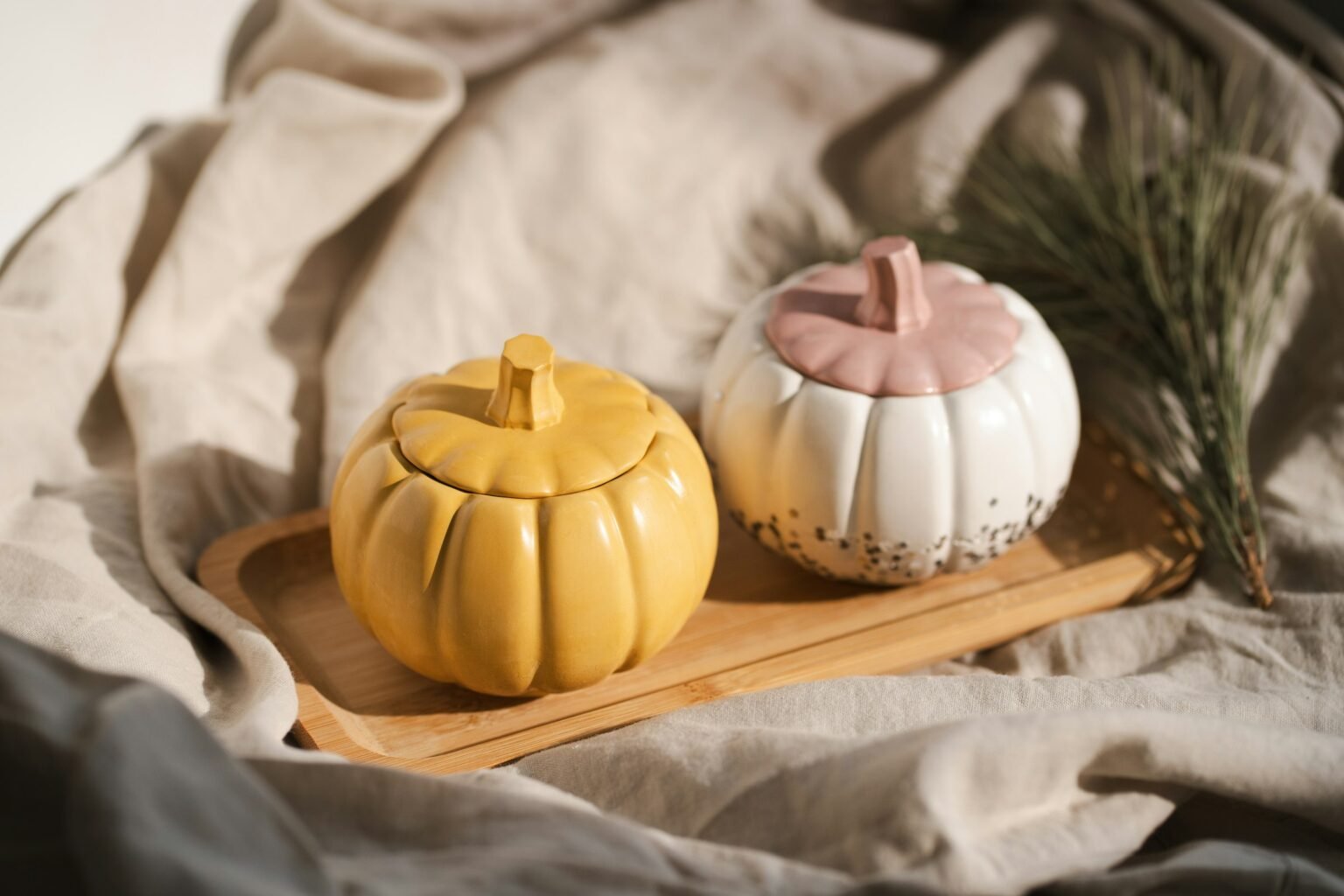 Fall wax melts mood: two ceramic pumpkin jars on a wooden tray with soft linen
