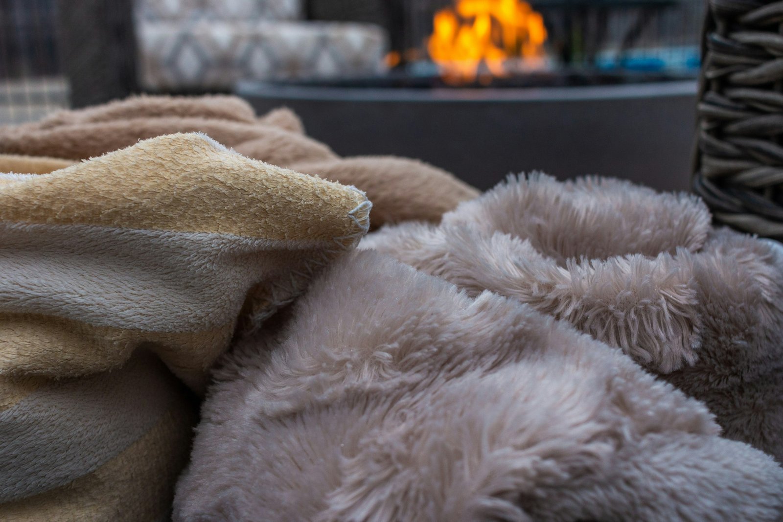 Faux fur throw for couch and patio lounging: soft taupe and cream faux fur blankets piled up on a chilly evening