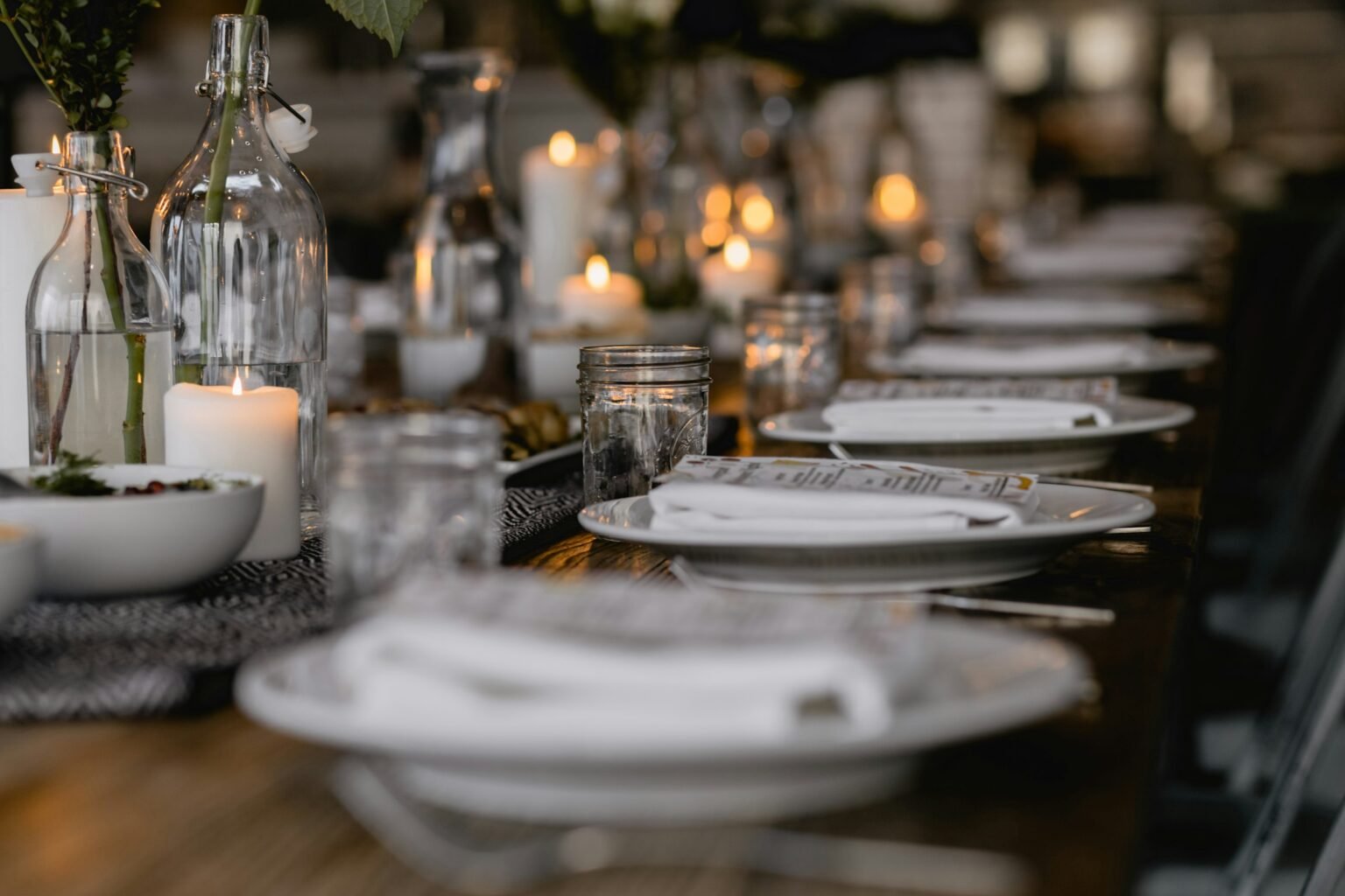 Flameless taper candles look on a long dining table set for dinner