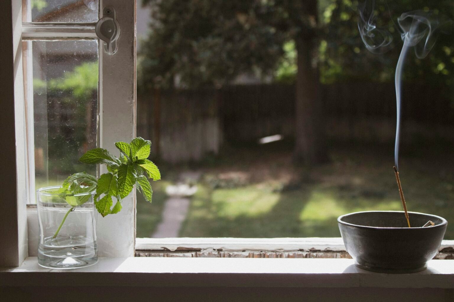 Frankincense and myrrh incense idea: a single incense stick burning in a bowl on a bright windowsill