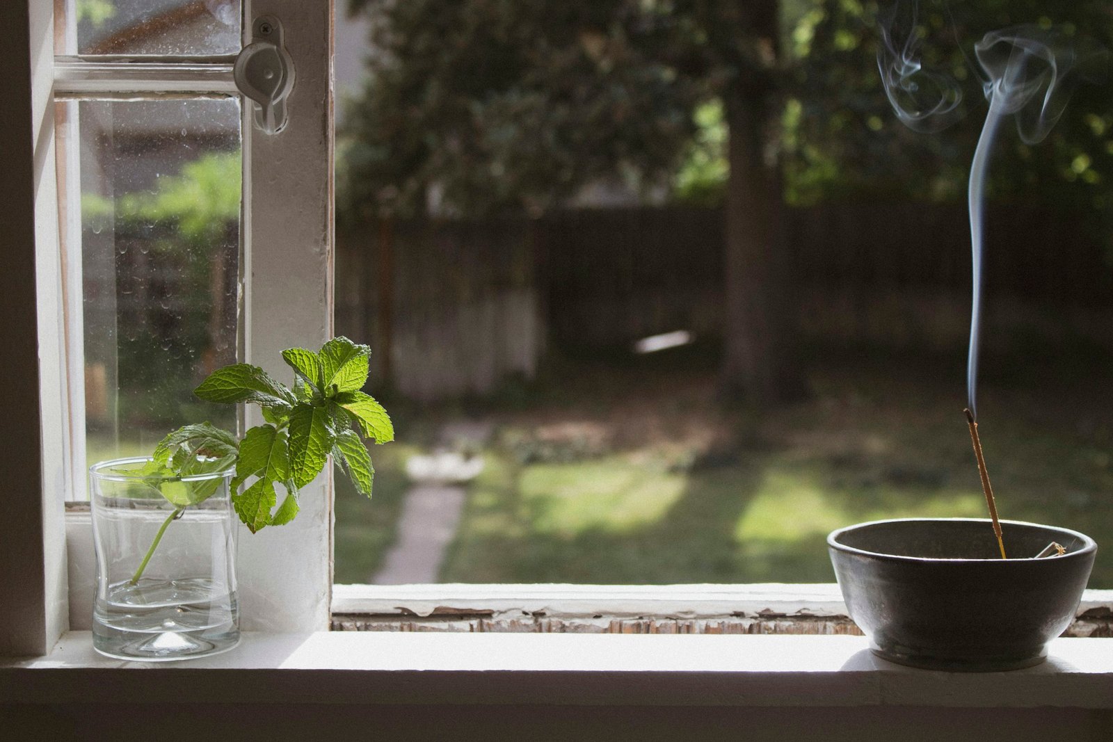 Frankincense and myrrh incense idea: a single incense stick burning in a bowl on a bright windowsill