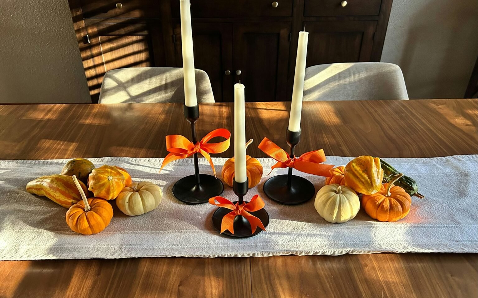 Halloween table decor ideas with candlesticks, pumpkins and gourds on a runner