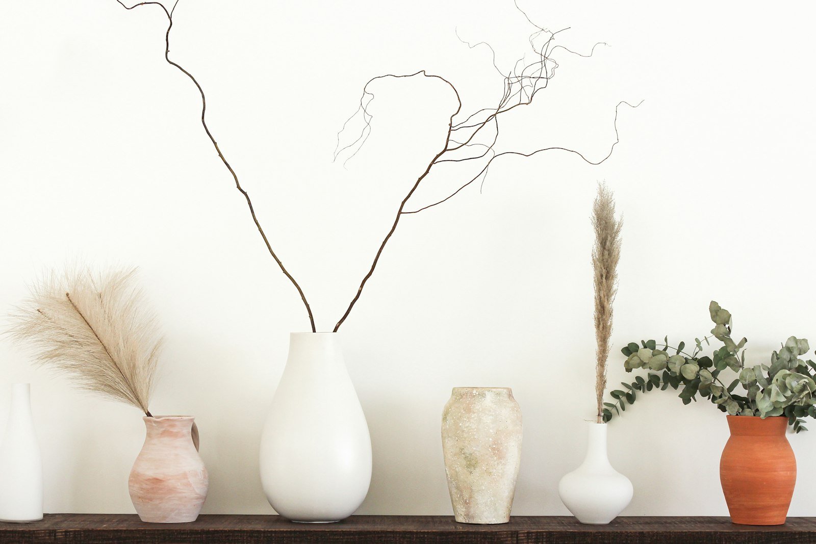 Home decor gifts for mom: neutral ceramic vases with dried stems on a wood shelf
