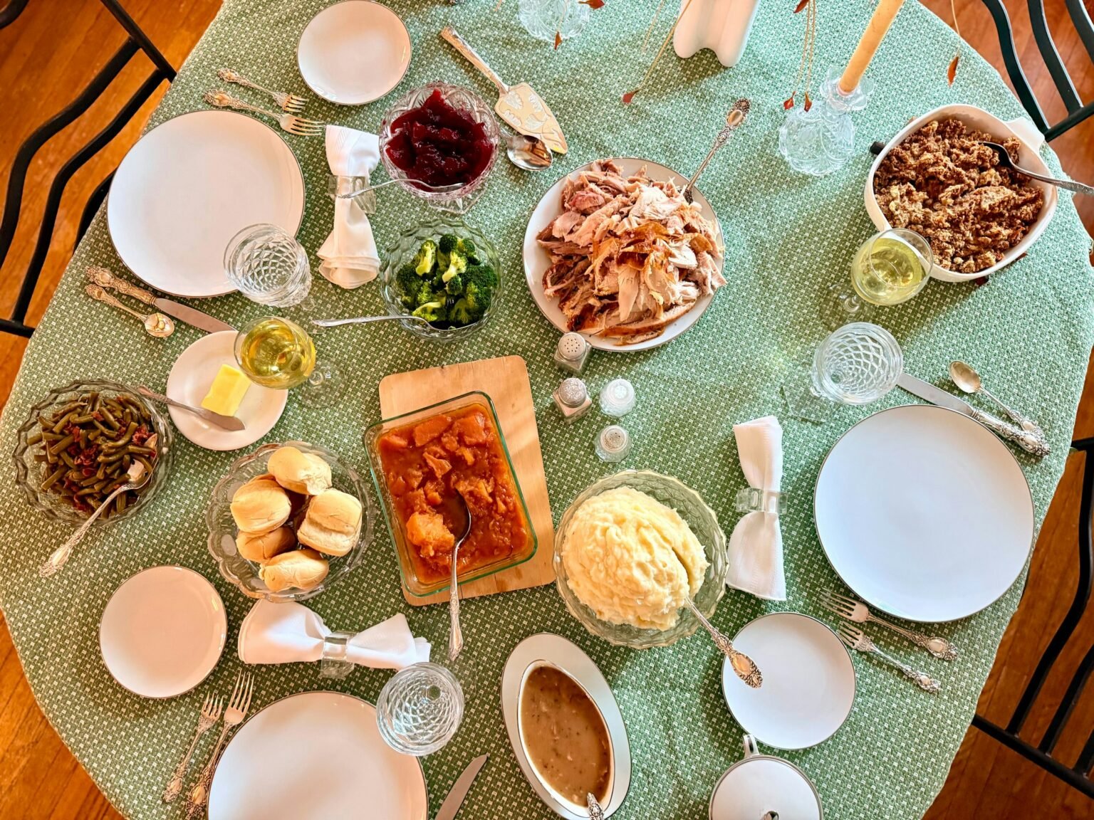 Thanksgiving hostess gift ideas: a Thanksgiving dinner table set with turkey, sides and plates