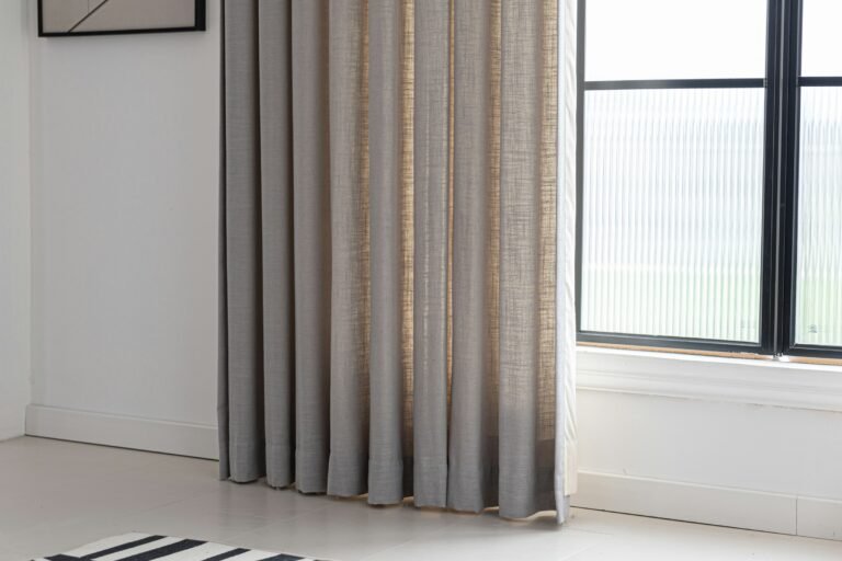 Linen blackout curtains in a textured natural tone hanging beside a bright black-framed window