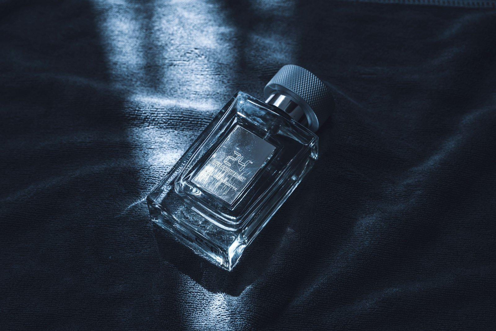 Glass perfume bottle with a silver cap on dark fabric, a mood for warm amber saffron perfume