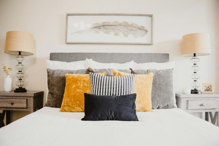 Lumbar pillow insert idea: a black velvet lumbar pillow in front of yellow and gray pillows on a white bed