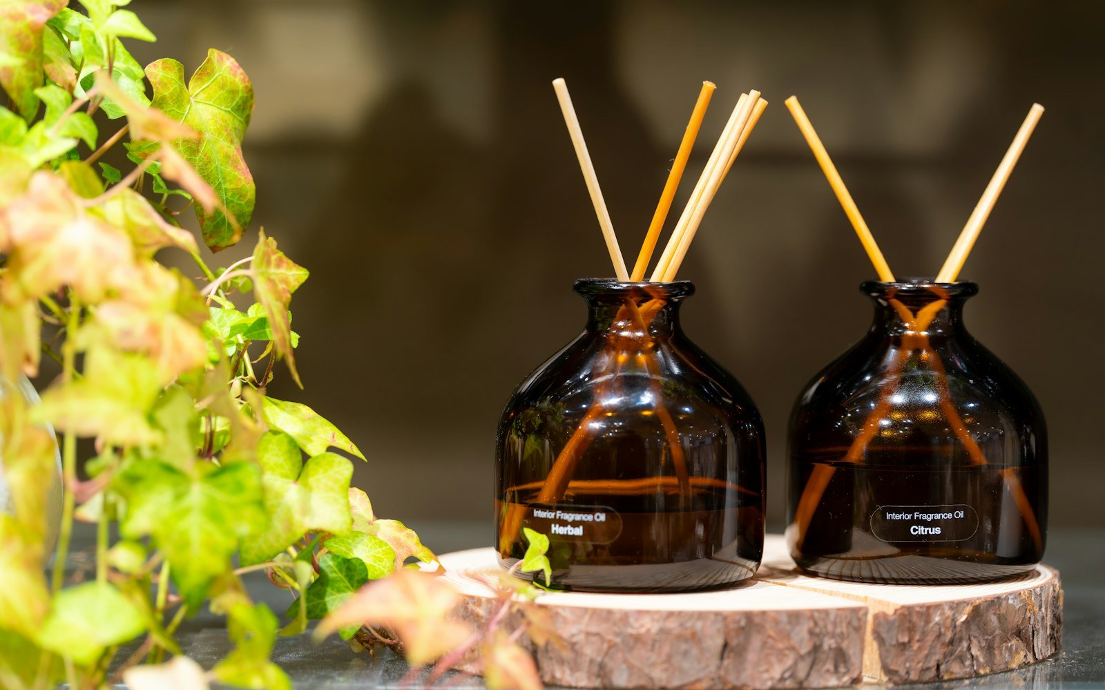 Best luxury reed diffusers: two amber glass bottles with wooden reeds beside trailing ivy