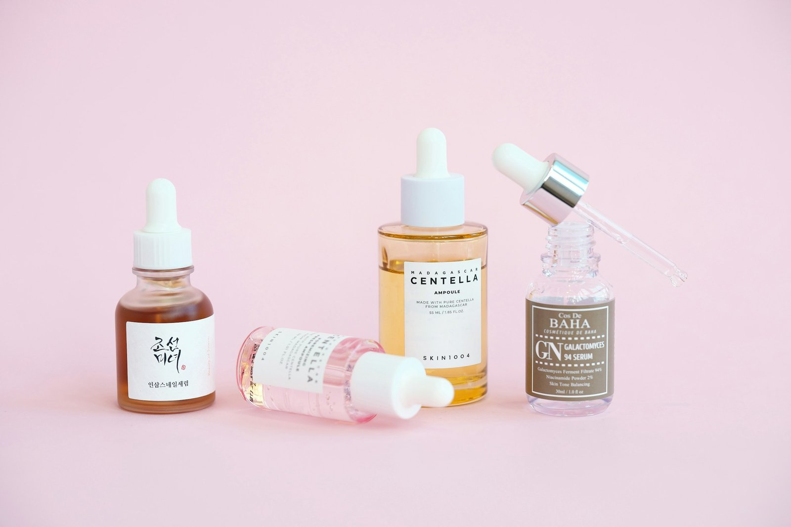 Luxury Korean skincare gift set ideas: four serum dropper bottles on a soft pink background