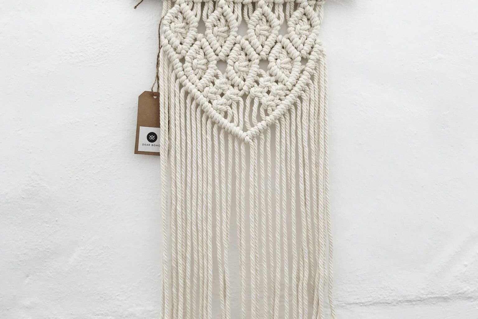 Macrame photo display styling idea: a woven macrame hanging on a light wall