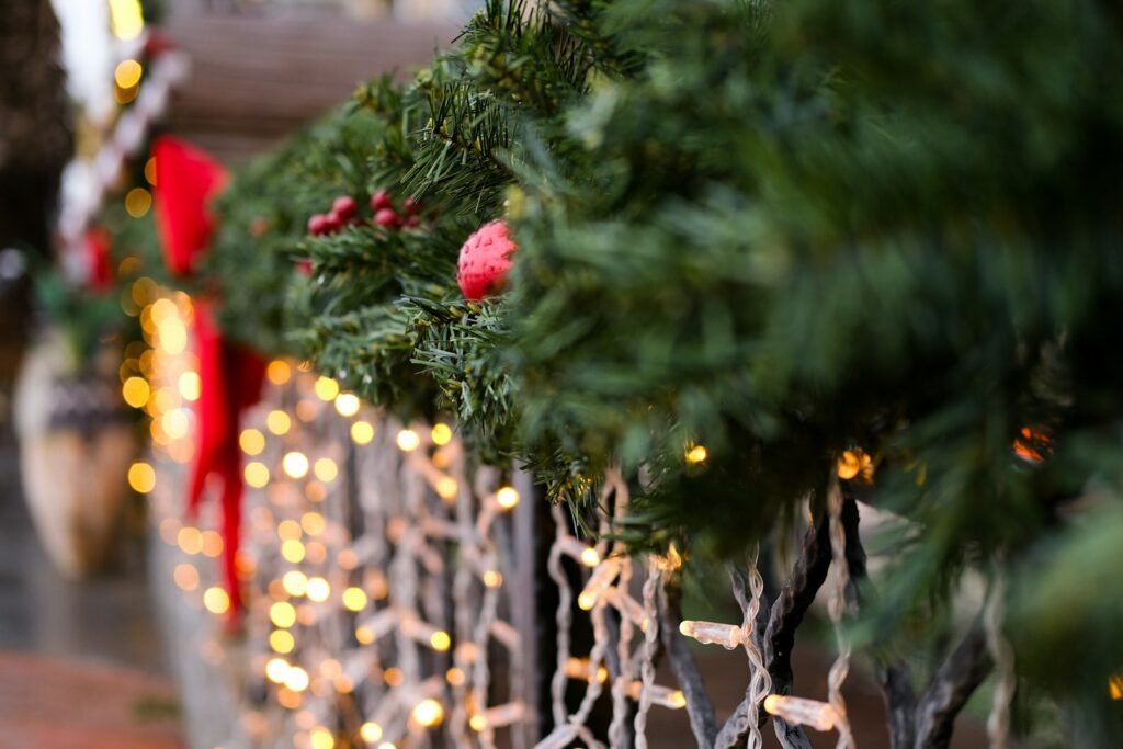 Christmas garland for staircase railing with red velvet bows, berries and warm string lights