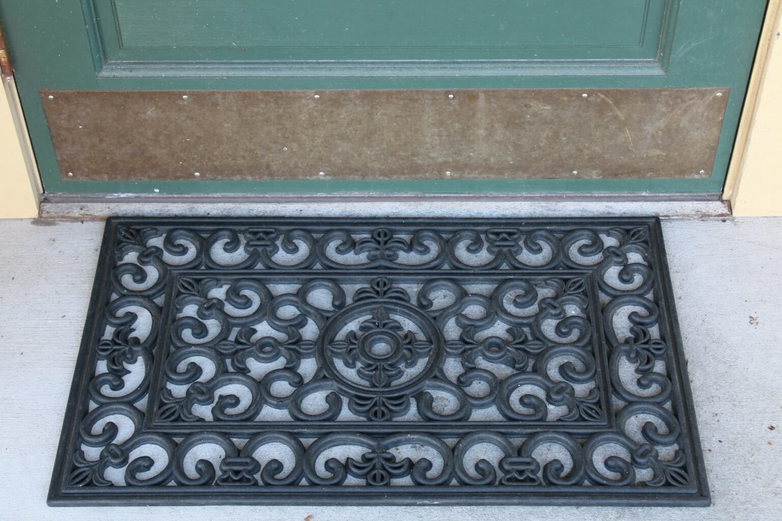 Black outdoor door mat sitting next to a front door