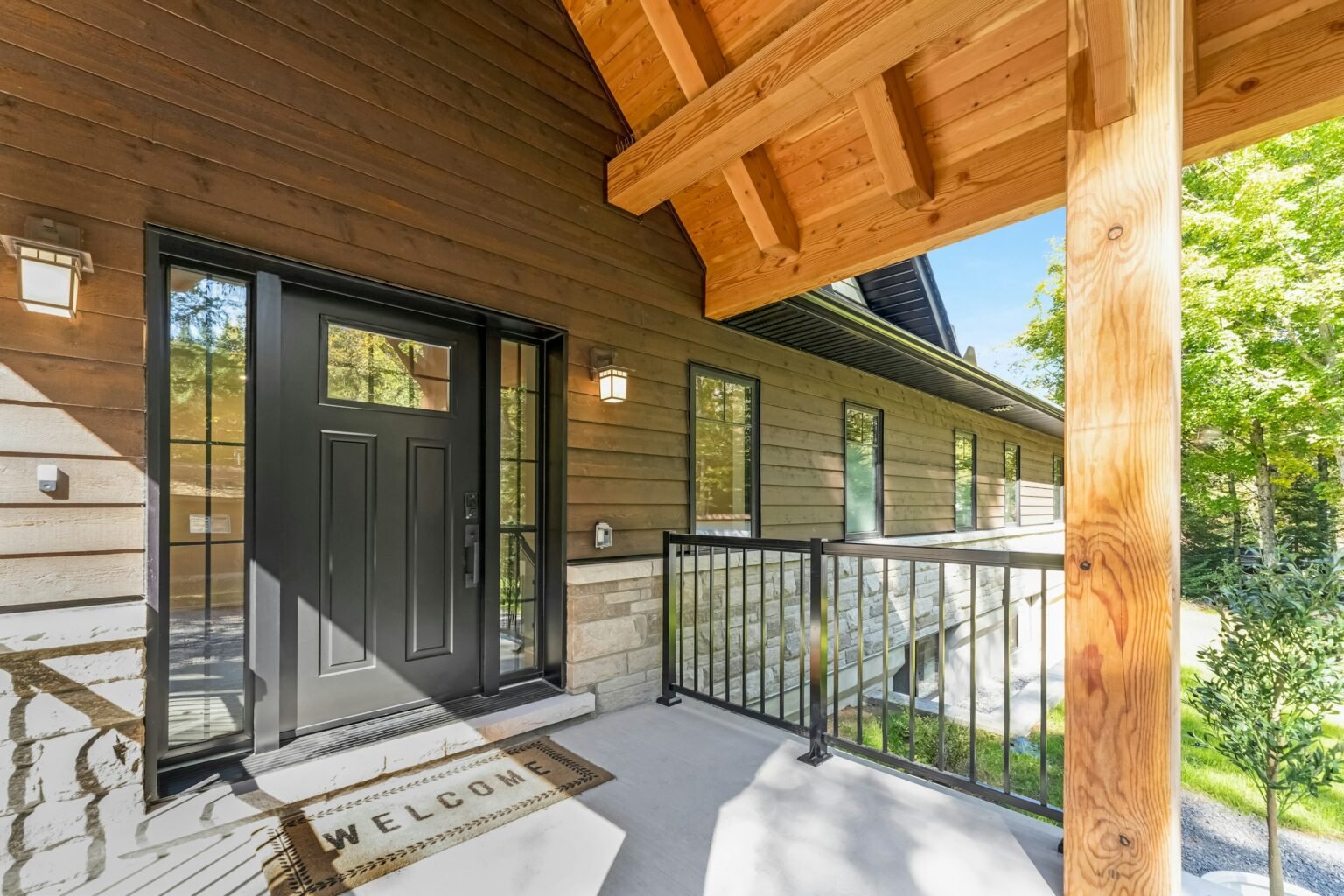 Outdoor door mat style idea: a black front door with a mat on a wooden porch