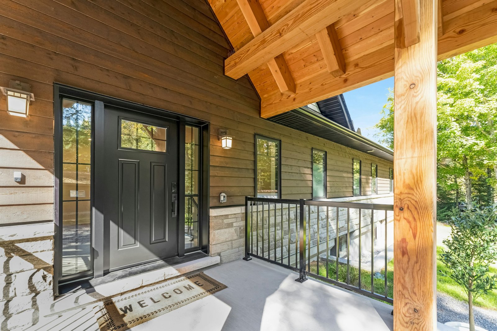 Outdoor door mat style idea: a black front door with a mat on a wooden porch