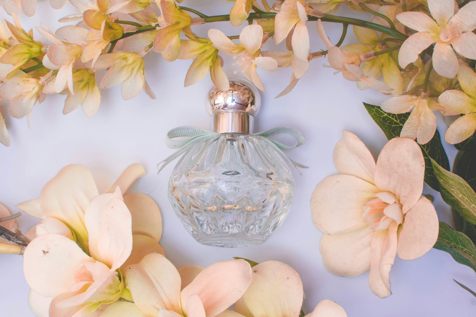 Perfumes that smell expensive: a cut-glass perfume bottle surrounded by pale peach flowers