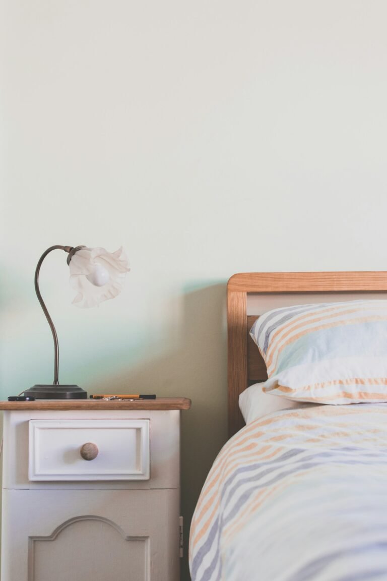 Rechargeable table lamp on a nightstand next to a bed