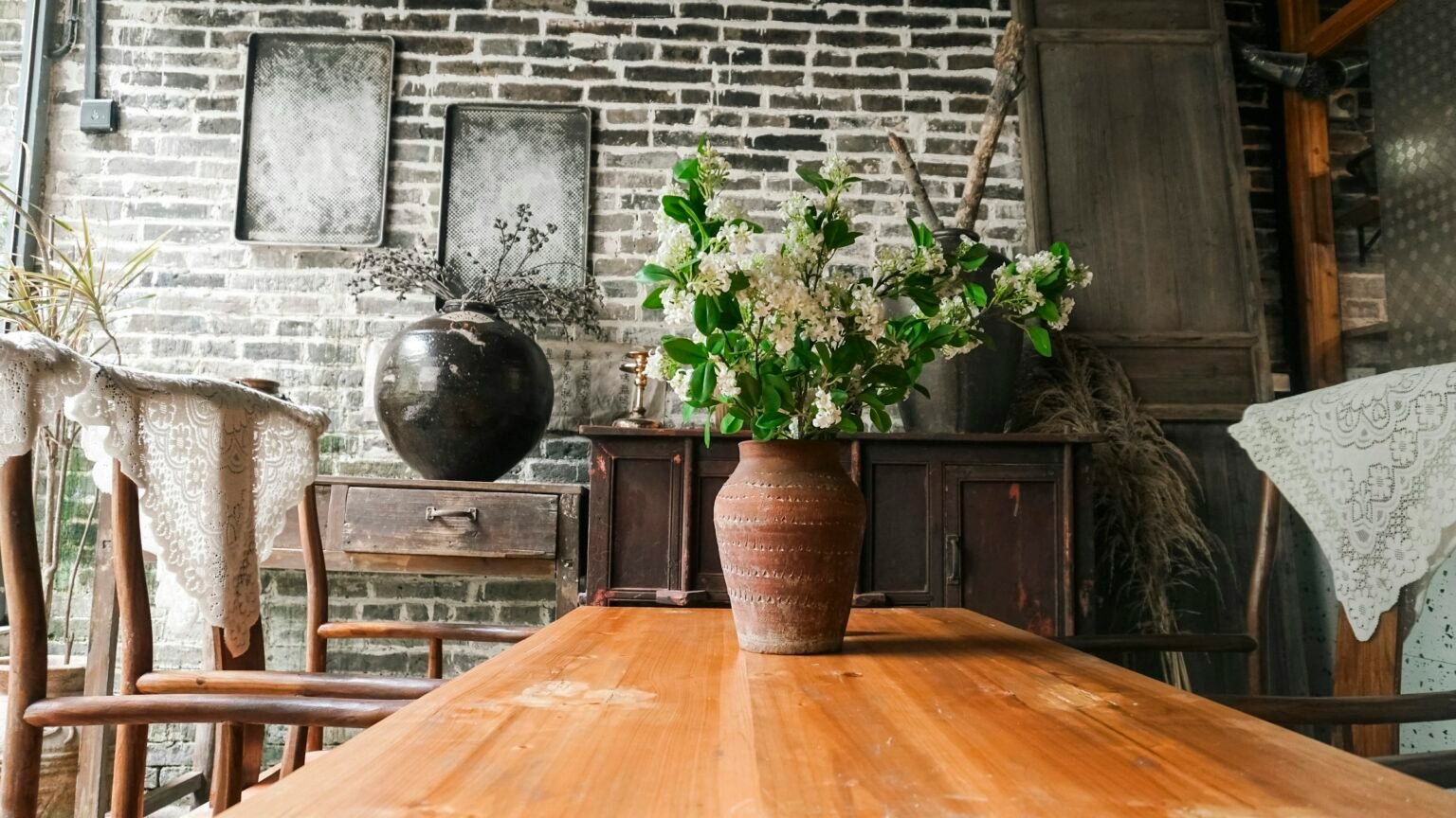 Rustic ceramic vase style: wooden table with white flowers in a rustic interior