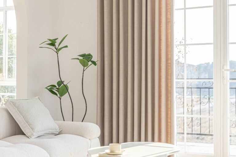Sliding glass door curtains in natural linen beside a glass balcony door in a bright white living room