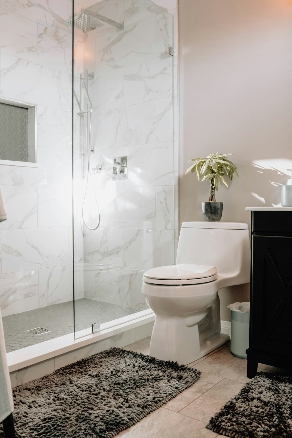A glass shower with marble tile in a small bathroom