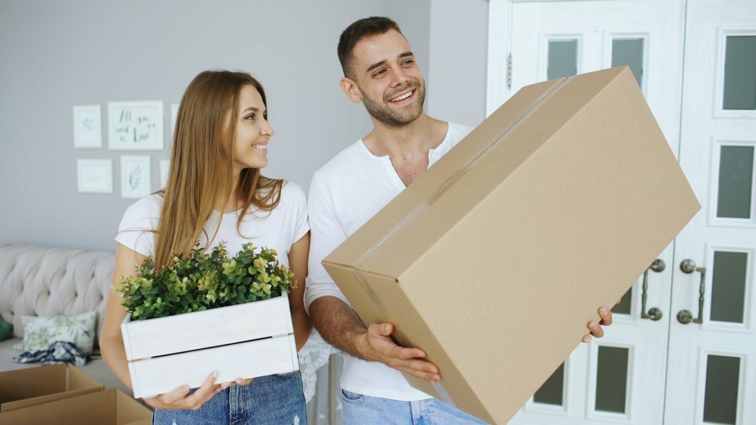 Couple carrying a large box and a plant