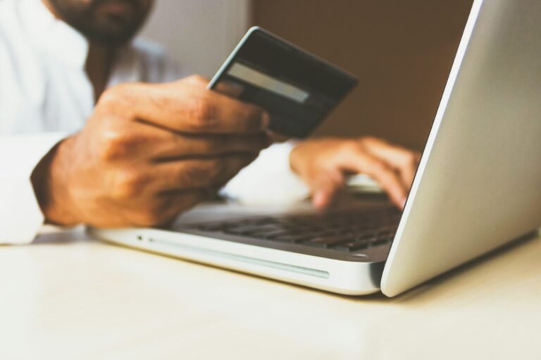Person using a laptop and holding a card