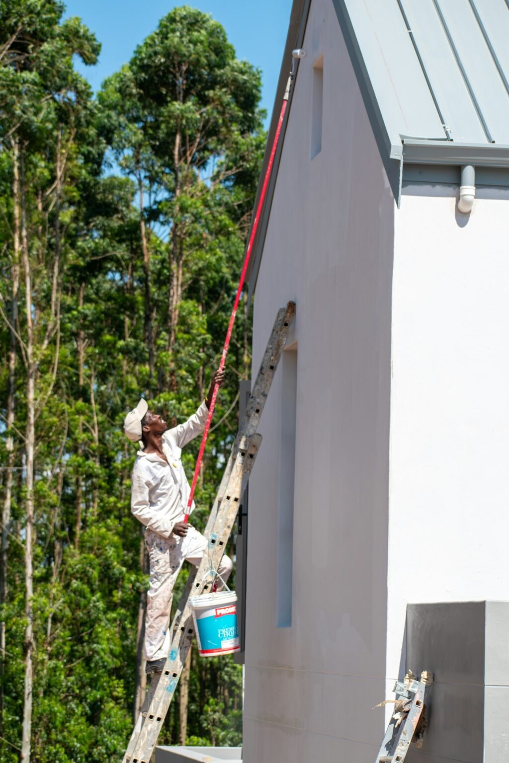 Cost to paint house exterior – Painter working on a house exterior