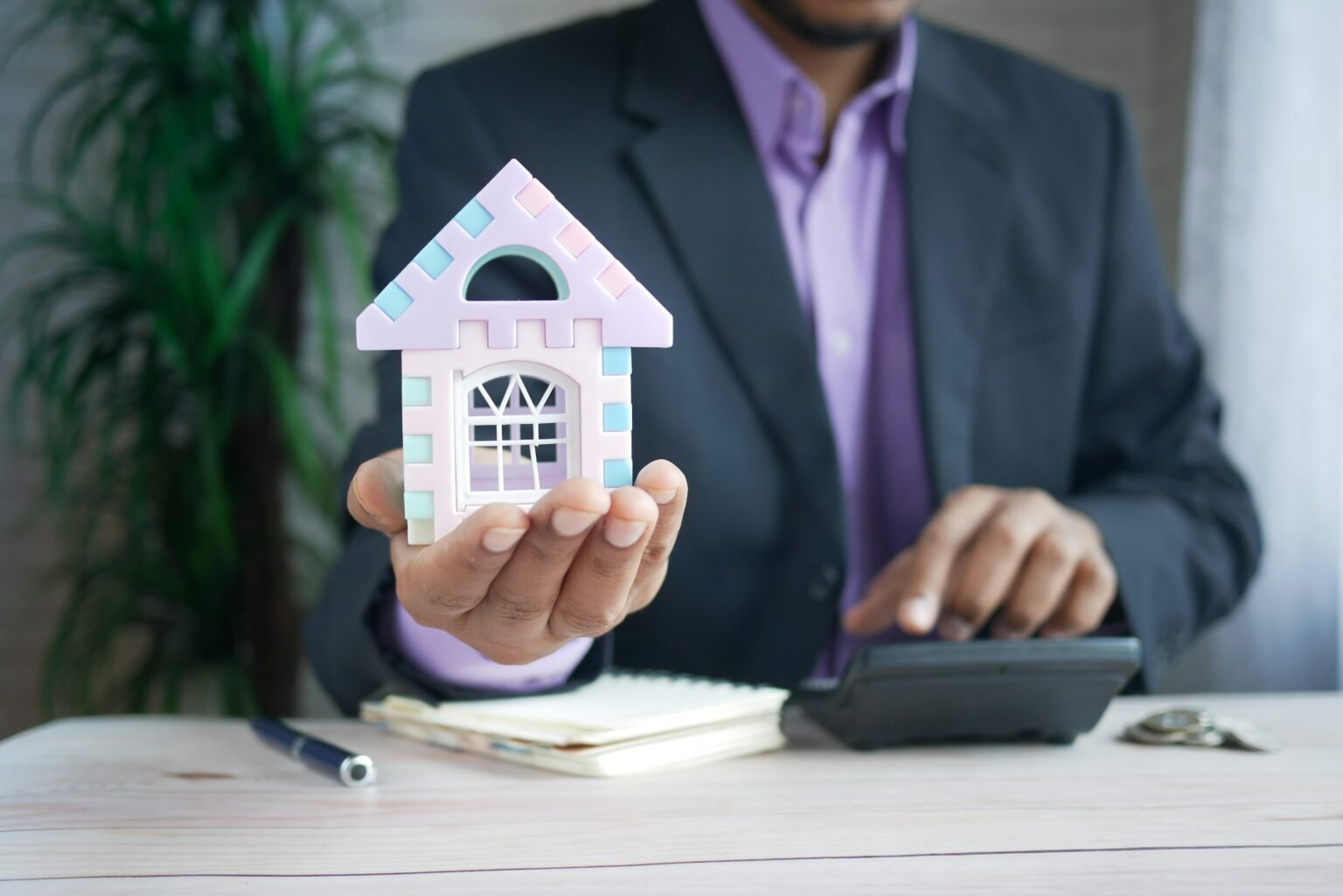 Man holding a model house at a desk