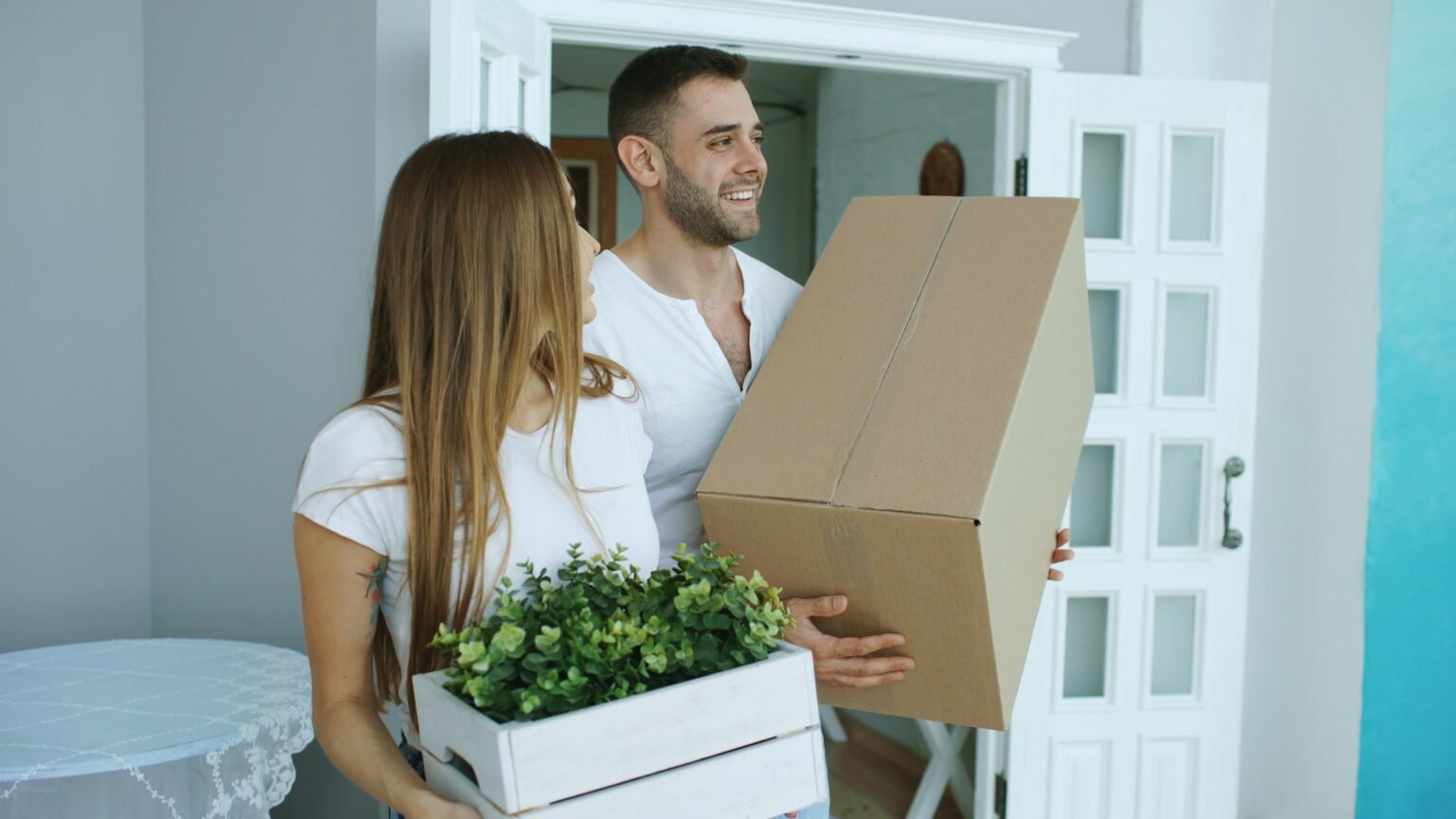 Couple carrying moving boxes into a new home