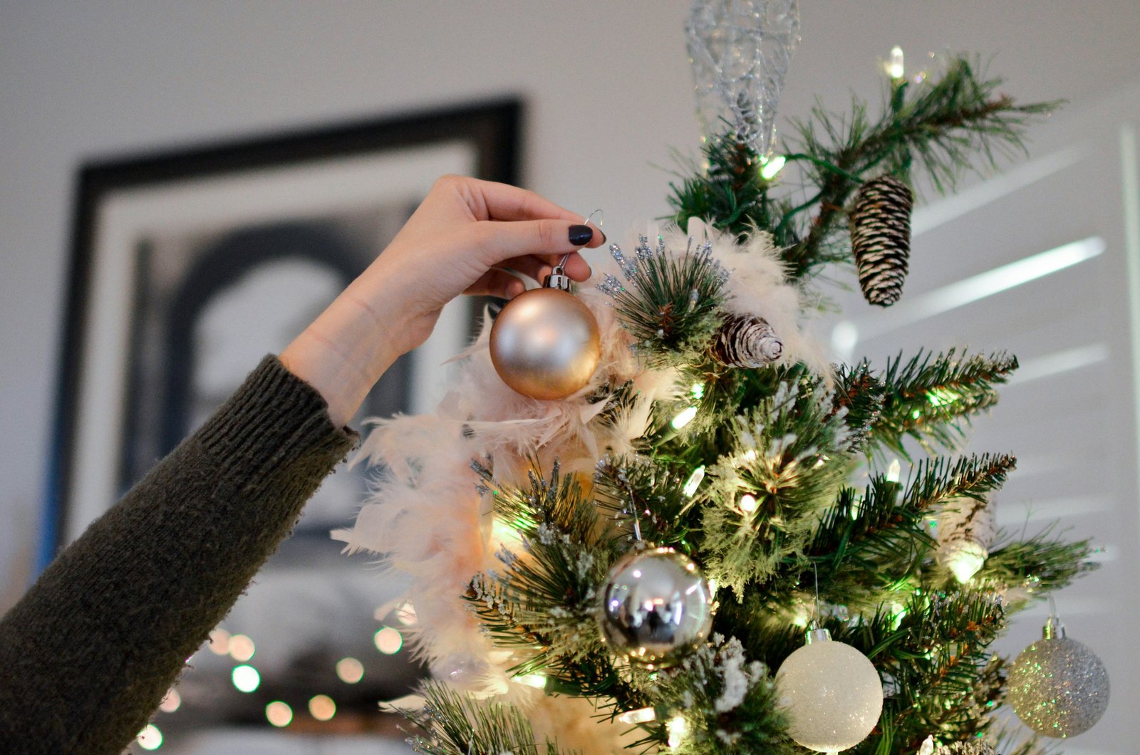 Person putting an ornament on top of a Christmas tree