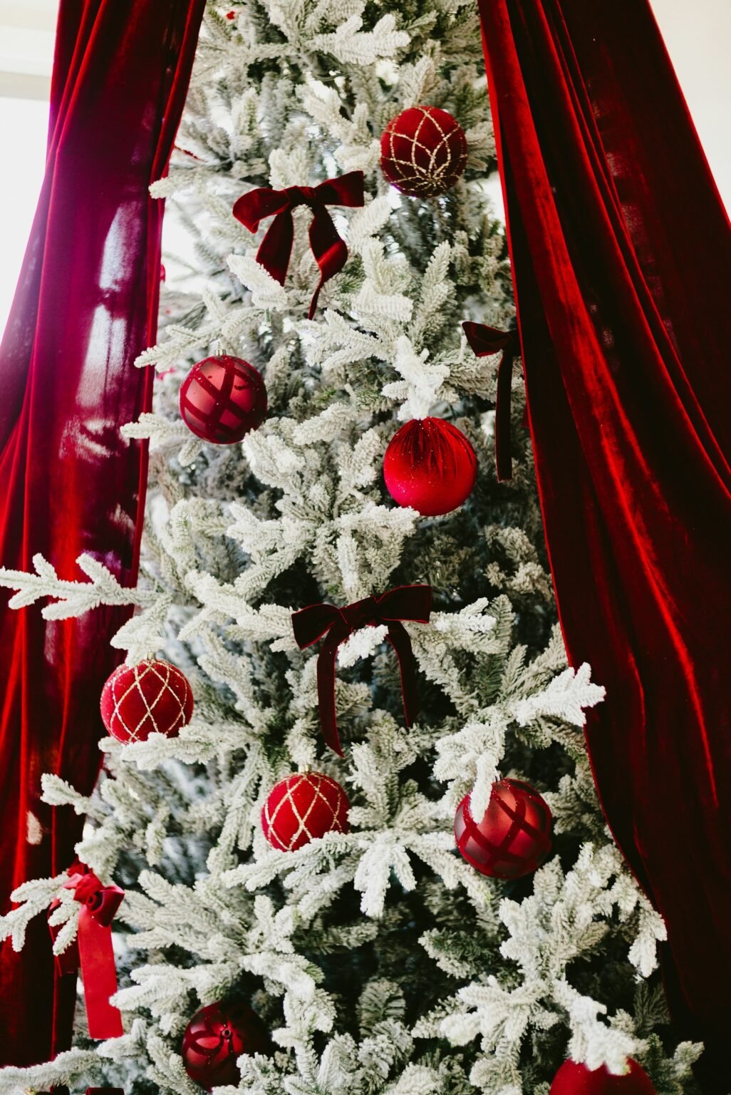 Flocked Christmas tree with red ornaments and bows