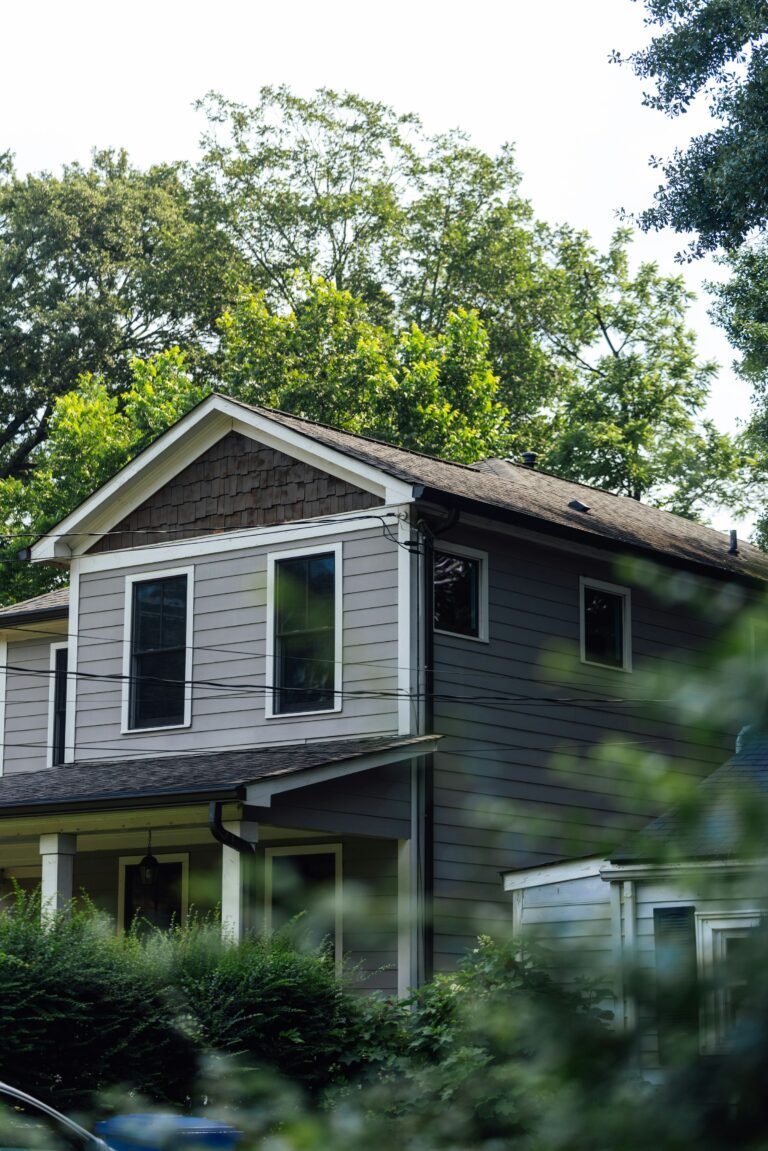 Gray two-story house surrounded by trees