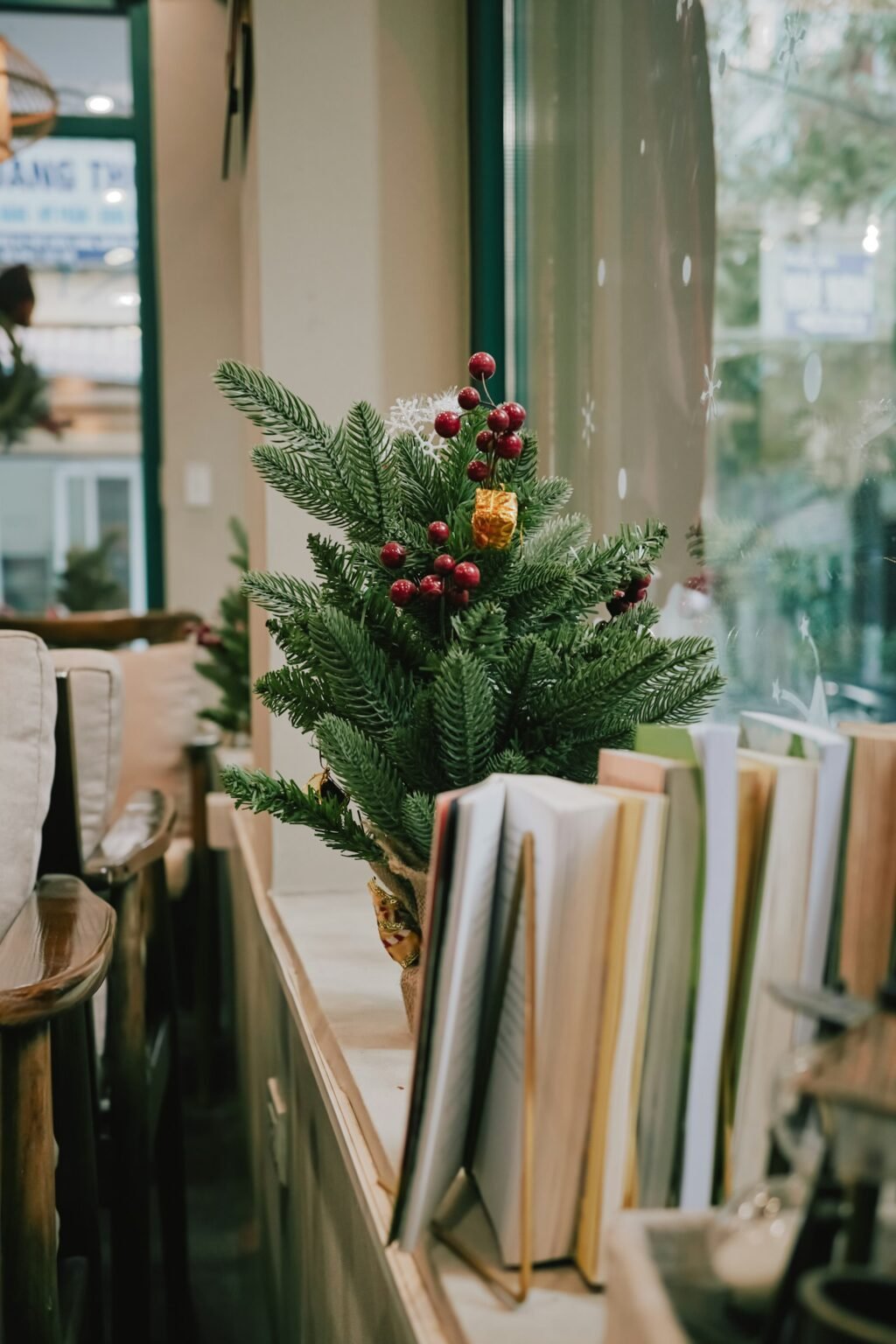 Small Christmas tree with berries next to books